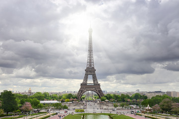 Fototapeta na wymiar Paris, France. Panoramic image of Eiffel tower with dramatic sky grey clouds with sun beams. Symmetrical balanced picture was taken from the axis of fountains of Trocadero in Spring.