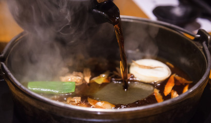 Selective Focused Pot Pouring Soup on Japanese nabemono hotpot dish of thinly sliced meat boiled in water served with dipping sauces, known as Shabu-Shabu. Traditional Japan Soup Food Menu concept