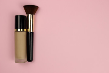 Foundation in a glass bubble and a makeup brush on a pink background