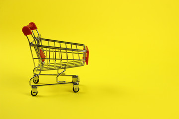 Mini supermarket cart, trolley on a yellow background. Purchases