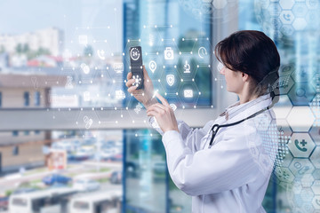 Doctor works in a mobile device with medical icons .