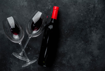  Bottle of red wine and glasses with  wine on a stone background. Top view with copy space.
