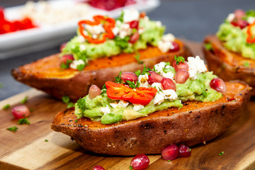 Healthy food - Baked sweet potatoes served with guacamole, feta cheese and pomegranate