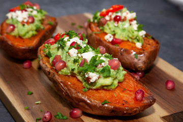 Healthy food - Baked sweet potatoes served with guacamole, feta cheese and pomegranate
