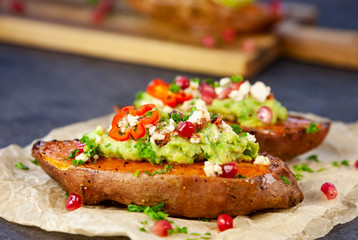 Healthy food - Baked sweet potatoes served with guacamole, feta cheese and pomegranate