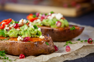 Healthy food - Baked sweet potatoes served with guacamole, feta cheese and pomegranate