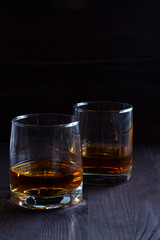 alcoholic drinks. glass of whiskey on a black background. two glasses of whiskey on a wooden background. horizontal orientation