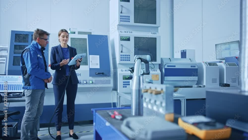 Poster modern factory: female project manager and male engineer standing, talking and using tablet computer