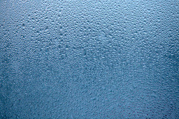 Close Up detail of moisture condensation problems, water drops, texture colorful water drop. Hot water vapor condensed on the cold window glass