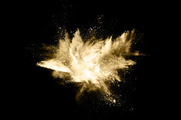Golden powder explosion on black background. Freeze motion.