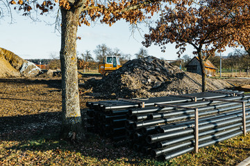 disused building site with pipes, bulldozer and a pile of dirt on a sunny day.