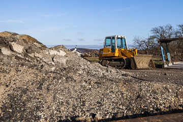 disused building site with bulldozer and a pile of dirt on a sunny day. © Moritz Klingenstein