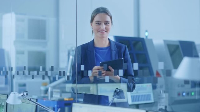 Modern Factory Office: Portrait of Young and Confident Female Industrial Engineer Standing and Holding Digital Tablet, She Smiles Charmingly at Camera. Industrial Factory with CNC Machinery Workshop