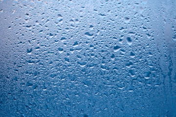 Drops of condensed steam, water drops. Close up detail of moisture condensation problems. Hot water vapor condensed on the cold window glass
