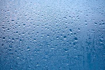 Drops of condensed steam, water drops. Close up detail of moisture condensation problems. Hot water vapor condensed on the cold window glass