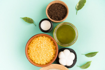 Cosmetic bath salt, grape gomaj for the face, coffee scrub for the body on a mint background. Spa...