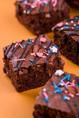 Chocolate brownie dessert with almond nut, chocolate glaze on an orange background.