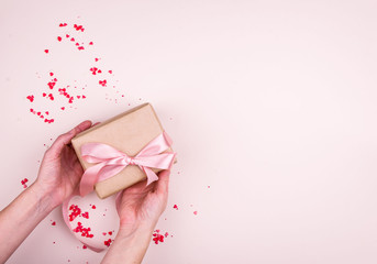 Concept for the holiday of All lovers, a place for writing, a view from above. Hearts, gentle background, gift, hands.