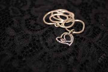  Double heart, silver pendant on a black background. Heart on a silver chain.