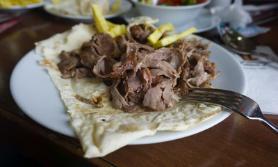 Turkish or Arabic traditional doner with pita bread / lavash on plate. Nutrition concept. Turkish, greek or middle eastern style doner kebab food on restaurant wooden table background.	