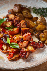 grilled octopus dish with small potatoes and vegetable salad. close up slices of fried octopus on a plate