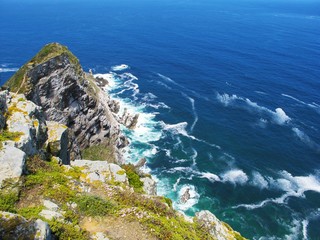 the raging waves crashing against the rocks.