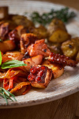grilled octopus dish with small potatoes and vegetable salad. close up slices of fried octopus on a plate
