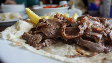Turkish or Arabic traditional doner with pita bread / lavash on plate. Nutrition concept. Turkish, greek or middle eastern style doner kebab food on restaurant wooden table background.	