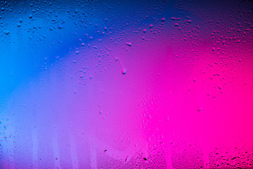 Glass with water drops on colorful background.