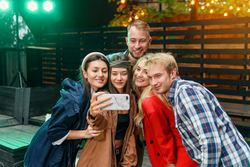 Fototapeta na wymiar Joyful stylish friends making selfie together at the party. Everyone are smiling and and enjoying their company.