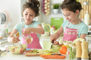 Portrait of girls preparing delicious fresh salad in kitchen