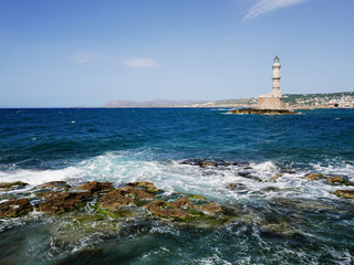 lighthouse on the coast with blue sea, waves and rocks. Beautiful landscape with seaside...