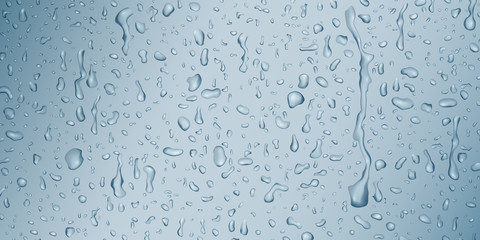 Background with drops and streaks of water in light blue colors, flowing down the surface