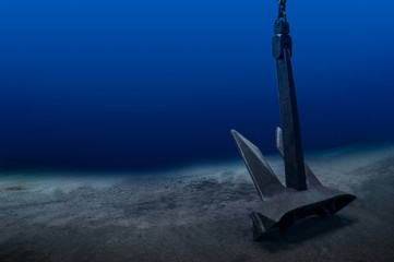 Ship anchor underwater on bottom in clean ocean water at anchorage. Marine shipping concept.