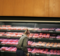 Woman purchasing a packet of meat at the supermarket	