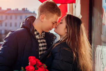 Valentines day loving couple kiss. Man giving bouquet of roses flowers to girlfriend on date in city. Womens day