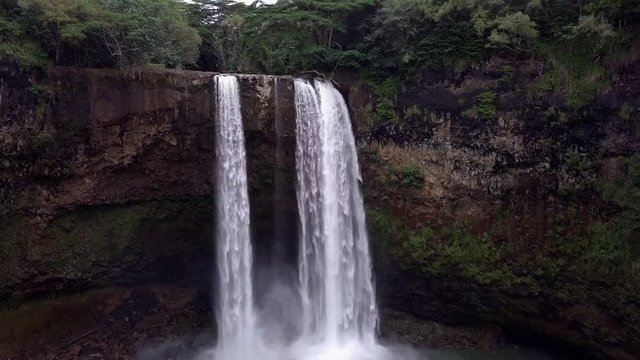 Wailua Falls, small hidden wild waterfall in middle of forest jungle on Kauai Island, Hawaii. Popular tourist landmark to visit. Drone Aerial Footage.