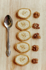 Obraz na płótnie Canvas Sliced bananas with peeled walnuts spread out on a wooden table.