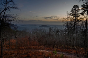 View of the hazy valley below on a cold winter morning. The sun is rising and lighting the rolling hills.