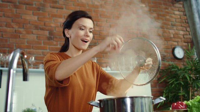 Woman cooking healthy food in kitchen. Girl salting hot meal in boiling pot.