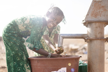 Gorgeous Native Malian African girl so happy to finally get healthy fresh water from an NGO tap in a village in Bamako, Mali