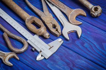 Many vintage craftsman tools stacked after work on blue wooden boards