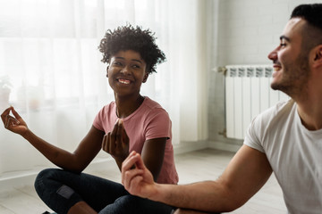Young smiling multi ethnic couple exercising together at home