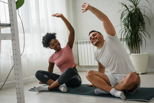 Young smiling multi ethnic couple exercising together at home