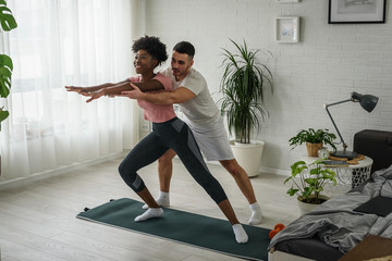 Young smiling multi ethnic couple exercising together at home