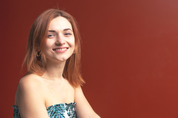 Naklejka premium Red-haired girl on a red background shows different emotions