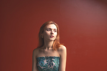 Fototapeta premium Red-haired girl on a red background shows different emotions