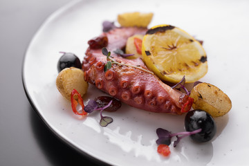 Octopus tentacles with lemon on a white plate