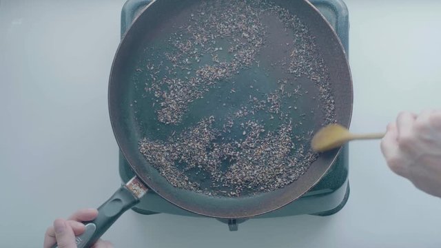 White Man's Hand Removes with a Wooden Spoon the Ingredients from the Black Frying Pan