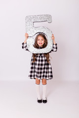 Grimacing baby shows tongue. Child with number 5. Birthday holiday celebration. Girl  holding in his hands figure of five.